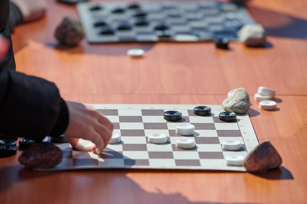 Buiten damwedstrijd op papier dambord op tafel close-up spelers handen