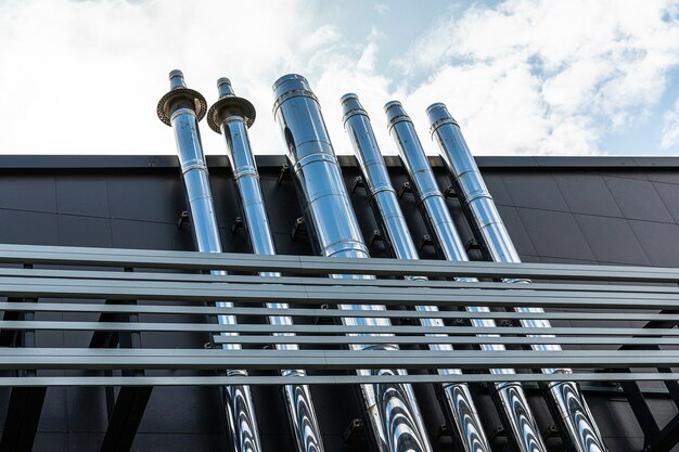 Buiten een groot gebouw steken veel metalen buizen uit