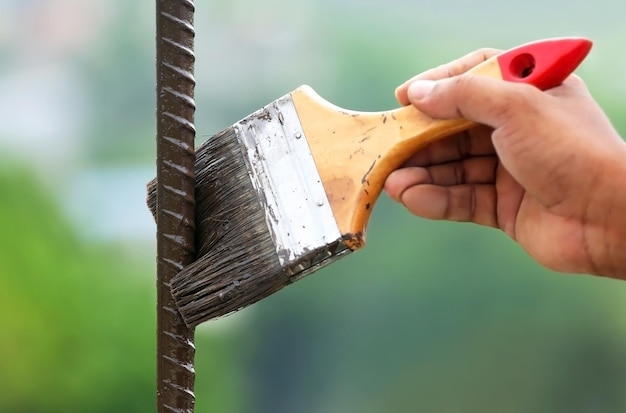 Buiten een ijzeren staaf schilderen met een borstel