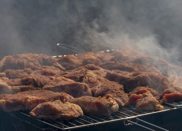 Buiten grillen van vlees. Rundvlees of varkensvleeslapjes vlees op grill met rook. Barbecue in de natuur.