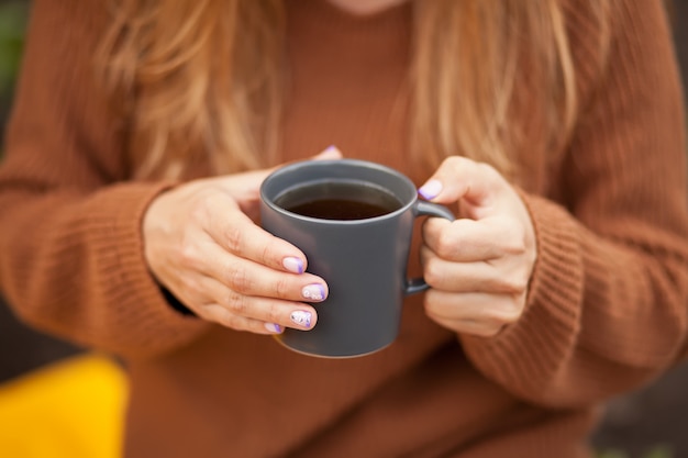 Buiten herfstpicknick. Jonge vrouw met mok hete koffie in een hand.