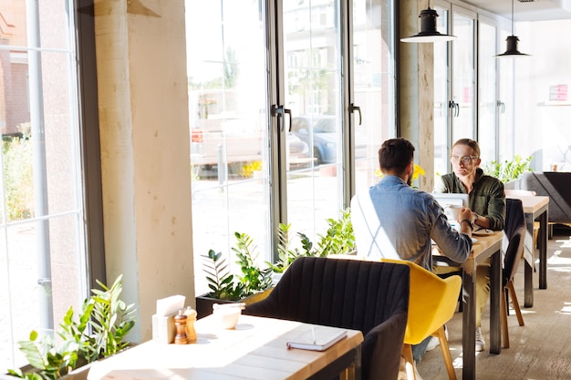 Buiten het kantoor. Aardige knappe mannen zitten in het café terwijl ze praten over werk buiten kantoor