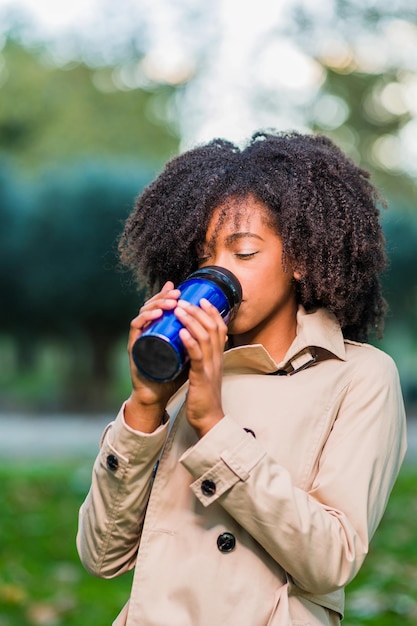 Buiten koffie drinken in de winter van een thermos latinx vrouw met afro krullend haar