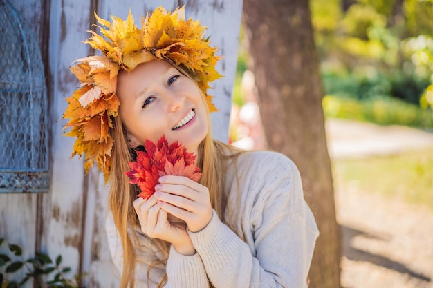 Buiten levensstijl close-up portret van charmante blonde jonge vrouw die een krans van herfstbladeren draagt