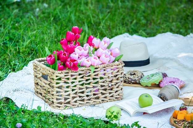 Buiten picknicken in een weelderig groen park met een smakelijke croissant, fruit, donuts en wijn op gras