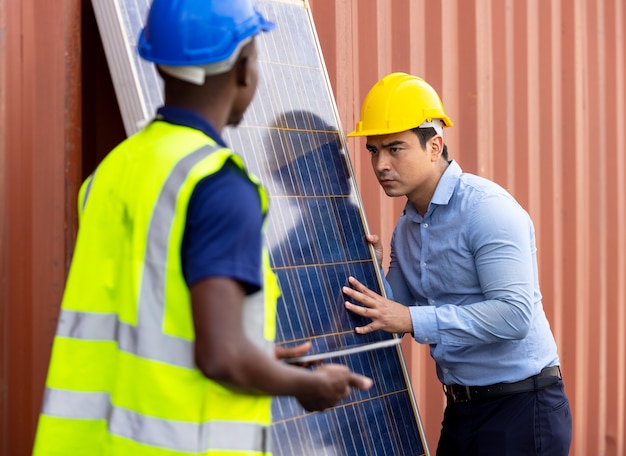 Buiten schot van zwarte Afrikaanse ingenieur inspecteren elektrische zonnepaneel dragen veiligheidshelm, beschermende lenzenvloeistof en veiligheidsuitrusting,