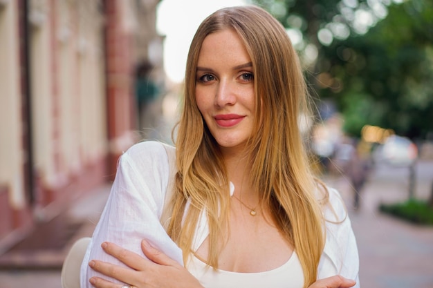 Buiten sensueel portret van elegante blonde vrouw posinf op straat, lente zomertijd, natuurlijke make-up.