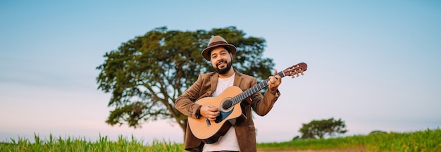 Buiten van een jonge Latijns-Amerikaanse man die gitaar speelt. Braziliaanse muzikant.