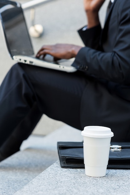 Buiten werken. Bijgesneden afbeelding van zakenman die op laptop werkt terwijl hij buiten op de trap zit