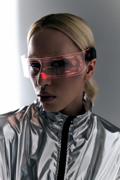 buitengewone vrouw met sci-fi bril in robot zilveren kleding kijkt naar de camera op de achtergrond