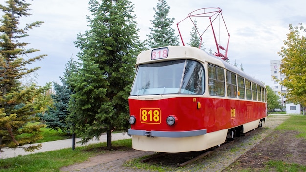 Buitenkant van een vintage rode en witte tram op het spoor als een tentoonstelling met nummer 818 erop, groen rondom, Chisinau, Moldavië