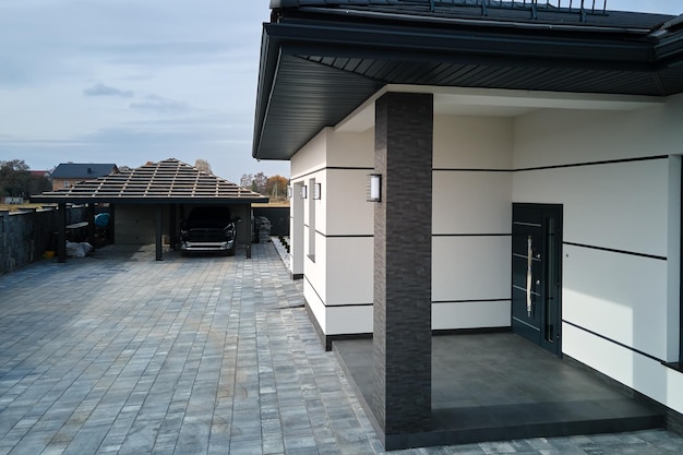 Buitenkant van modern eigentijds comfortabel huis met veranda, stijlvolle deur, geplaveide tuin en ramen met luiken