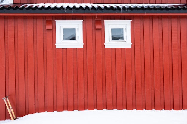 Buitenkant van rood vissershuis met wit raam en sneeuw of rorbuer in scandinavië