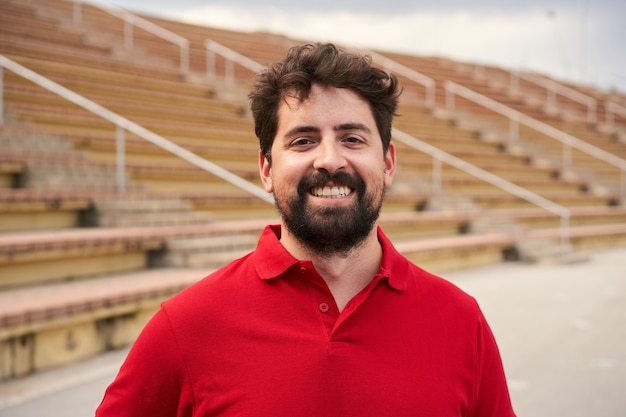 buitenportret van een Spaanse man in een rood shirt op de achtergrond van een stadion