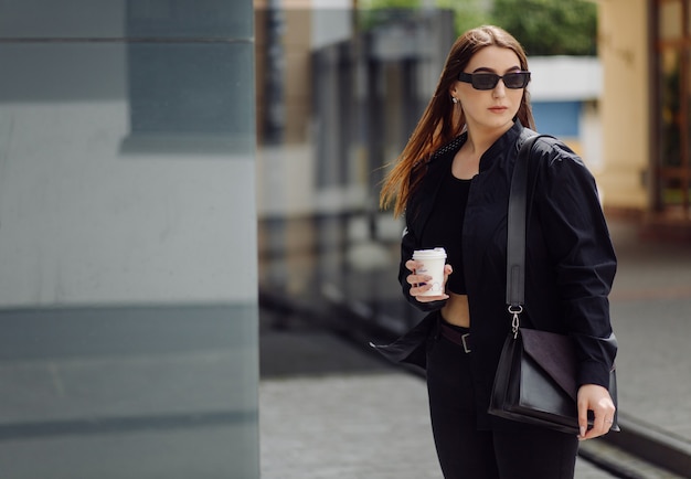 Buitenshuis lifestyle portret van prachtige brunette meisje. koffie drinken en wandelen door de stadsstraat.