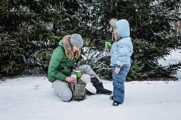 Buitenshuis winteractiviteiten voor familie, gelukkige familie, moeder, jongen, kind en hond die plezier hebben en