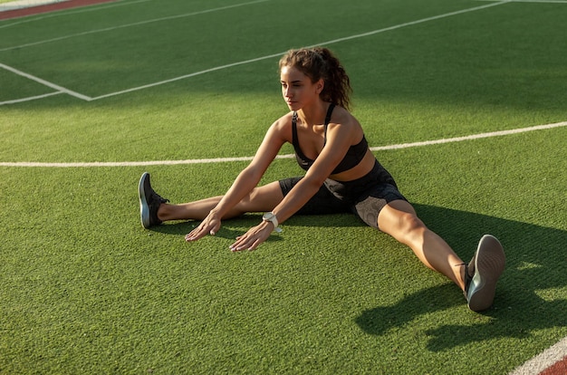 Buitentraining. Aantrekkelijk sexy fitnessmodel warmt op en rekt de spieren voor de training