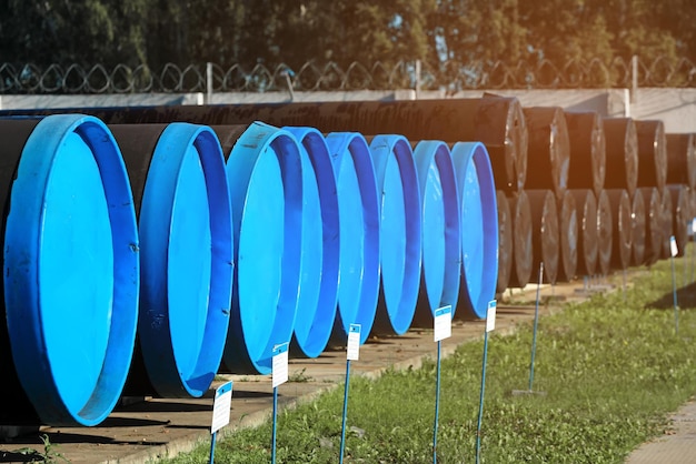 Buizen met grote diameter en pluggen liggen op een zomerdag in een open magazijn Opslag en levering van vergassingsmaterialen