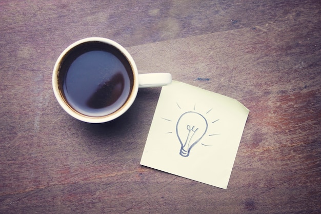 Лампочка на бумаге и чашке кофе