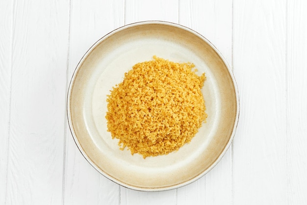 Bulgur garnish in a plate on a white wooden background