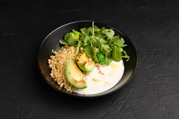 Bulgur con piatto caldo di avocado con avocado e bulgur su sfondo nero vista laterale