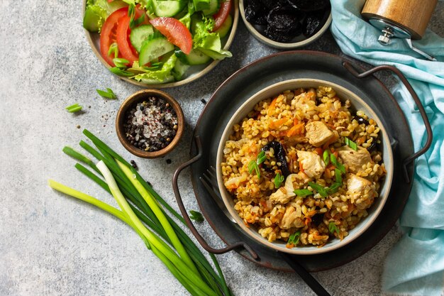 灰色の石またはスレートのカウンタートップに鶏肉の野菜とプルーンを添えたブルグル上面図コピースペース