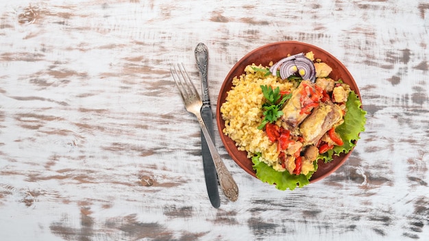 Bulgur with meat paprika cherry tomatoes and vegetables On a wooden background Top view Copy space