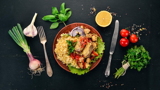 Bulgur with meat paprika cherry tomatoes and vegetables On a wooden background Top view Copy space