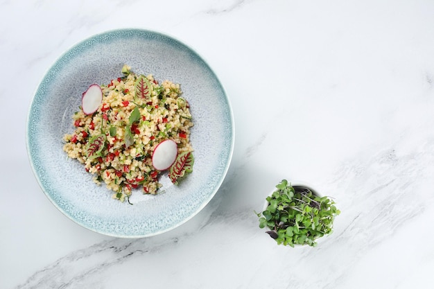 Bulgur with vegetables red pepper and radish on light marble background.