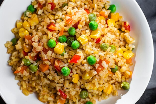 Bulgur with vegetables in a white plate close-up