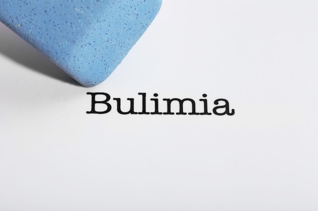 Bulimia word with eraser on white paper background