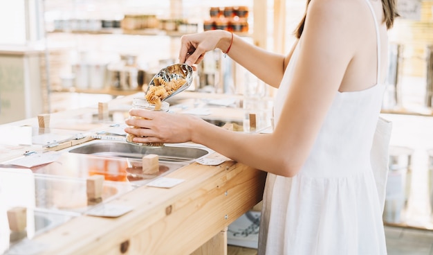 bulk products in zero waste shop woman buying dry goods in plastic free grocery store