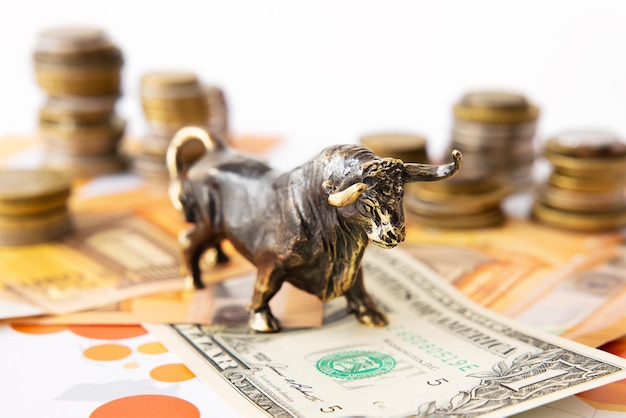 Bull standing on one dollar banknote with stacks of coins behind