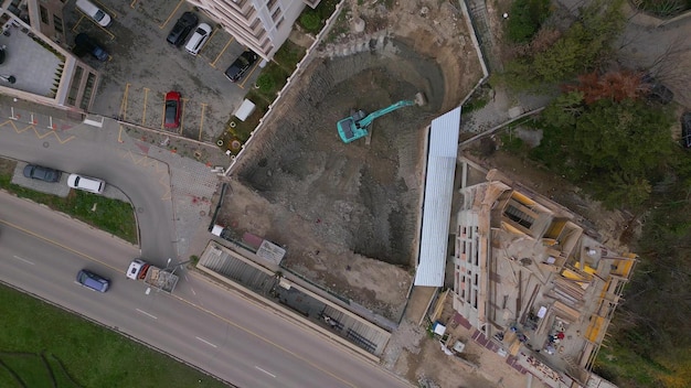 A bulldozer is digging a pit for the construction of another building in the middle of the city aerial view