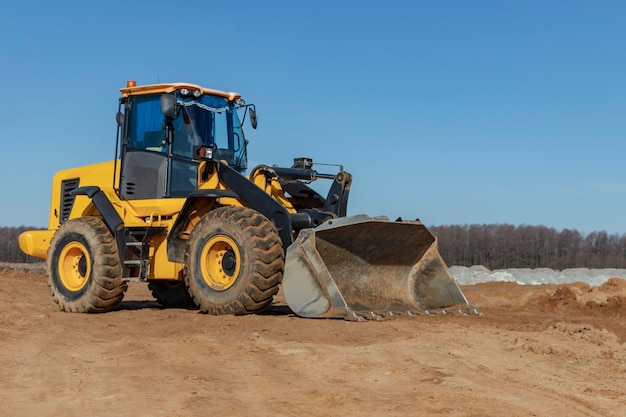 Bulldozer or loader moves the earth at the construction site against the blue sky An earthmoving machine is leveling the site Construction heavy equipment for earthworks