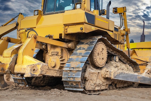 La macchina del bulldozer sta livellando il cantiere earthmover con macchinari pesanti da costruzione del primo piano del fondo del cielo