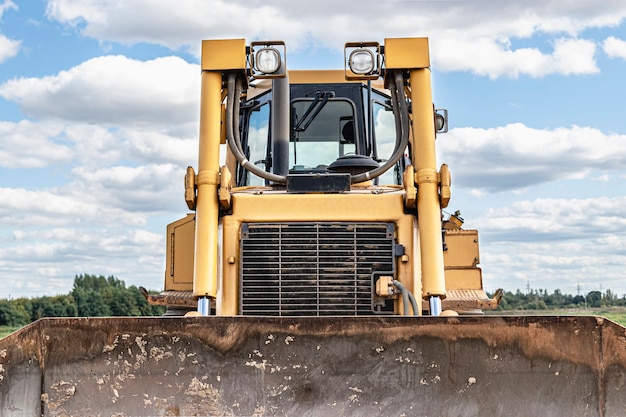 Bulldozer machine is leveling construction site. Earthmover with tractor is moving earth. Close-up. Construction heavy machinery.