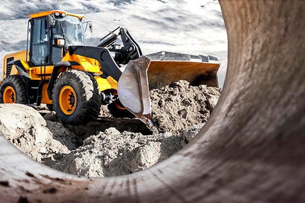 Bulldozer of lader beweegt de aarde op de bouwplaats tegen de avondrood Contrasterend beeld van een moderne lader of bulldozer Bouw zwaar materieel voor grondwerken