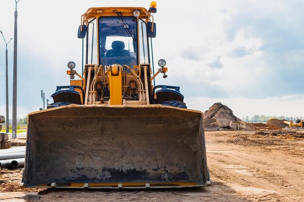 Bulldozer of lader beweegt de aarde op de bouwplaats tegen de blauwe lucht Een grondverzetmachine egaliseert de site Bouw zwaar materieel voor grondwerken