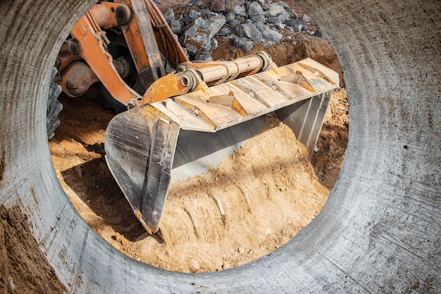 Bulldozer of lader beweegt de aarde op de bouwplaats tegen de blauwe lucht Een grondverzetmachine egaliseert de site Bouw zwaar materieel voor grondwerken