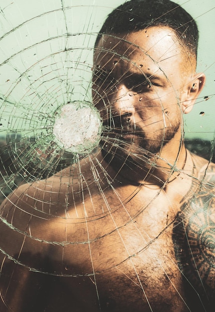 Bullet hole in glass. Destruction and crush test concept. Man style. Macho man glasscutter behind crushed glass. Sexy hispanic tattooed man behind broken glass.