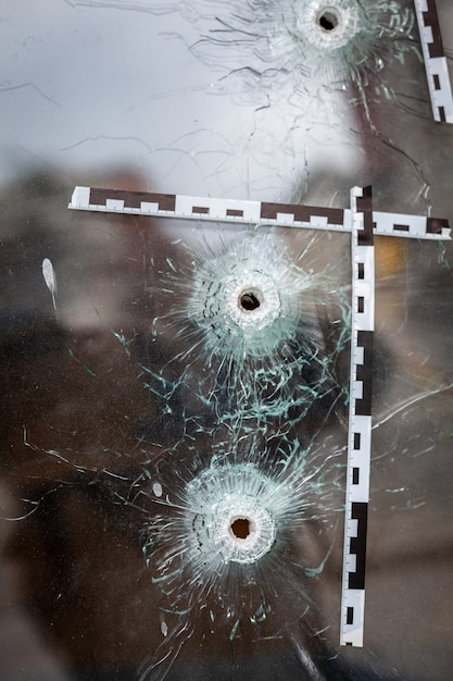 Bullet holes in a glass shop window marked with a police tape