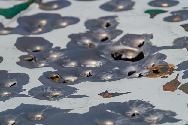 Photo bullet holes in the metal multiple bullet marks on the car body peeling green bullet holes texture metal shooting shooting on the street shot target bullet grapeshot gunpowder background