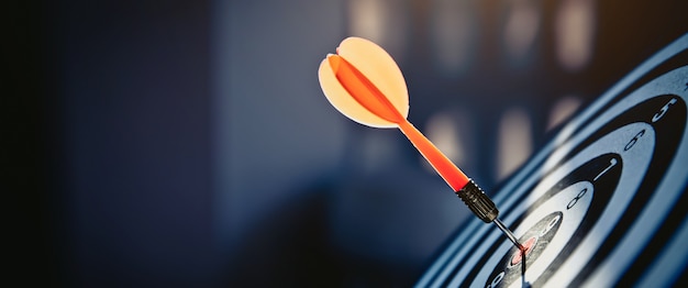 Photo bullseye has dart arrow throw hitting the center of a shooting target.