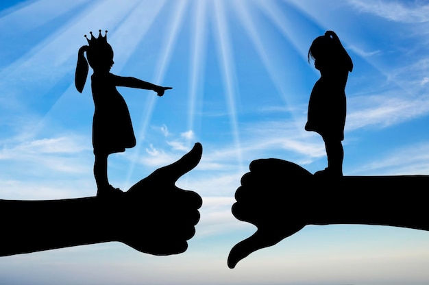 Bullying school A girl with a crown on her head points her finger at another crying girl