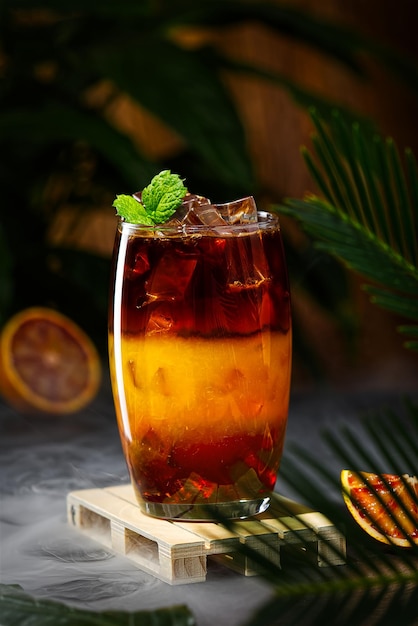 Bumble coffee with ice on a dark tropical background espresso orange juice and syrup in layers