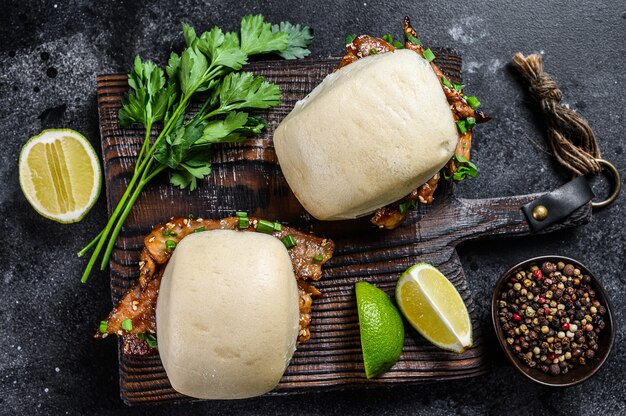 Bun bao steamed with pork belly and vegetables. Black background. Top view.