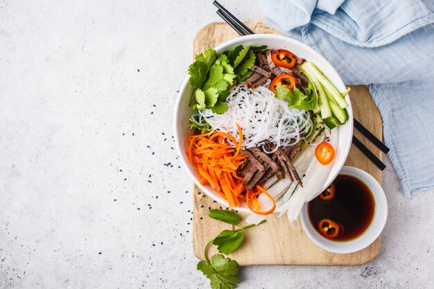 Bun cha saladeschaal. Vietnamese rijstnoedel met rundvlees en Spaanse pepersgroenten salade in witte kom