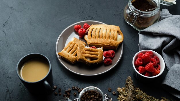 Bun with cream and raspberries on a dark background