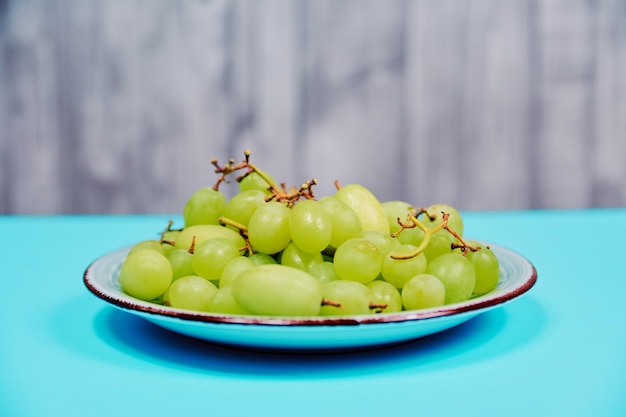 A bunch of appetizing white table grapes on an oblique blue and grey background